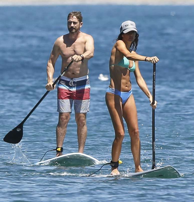 Gerard Butler e a namorada, Morgan Brown, praticam stand up paddle em praia de Malibu, nos Estados Unidos, no último sábado (15)