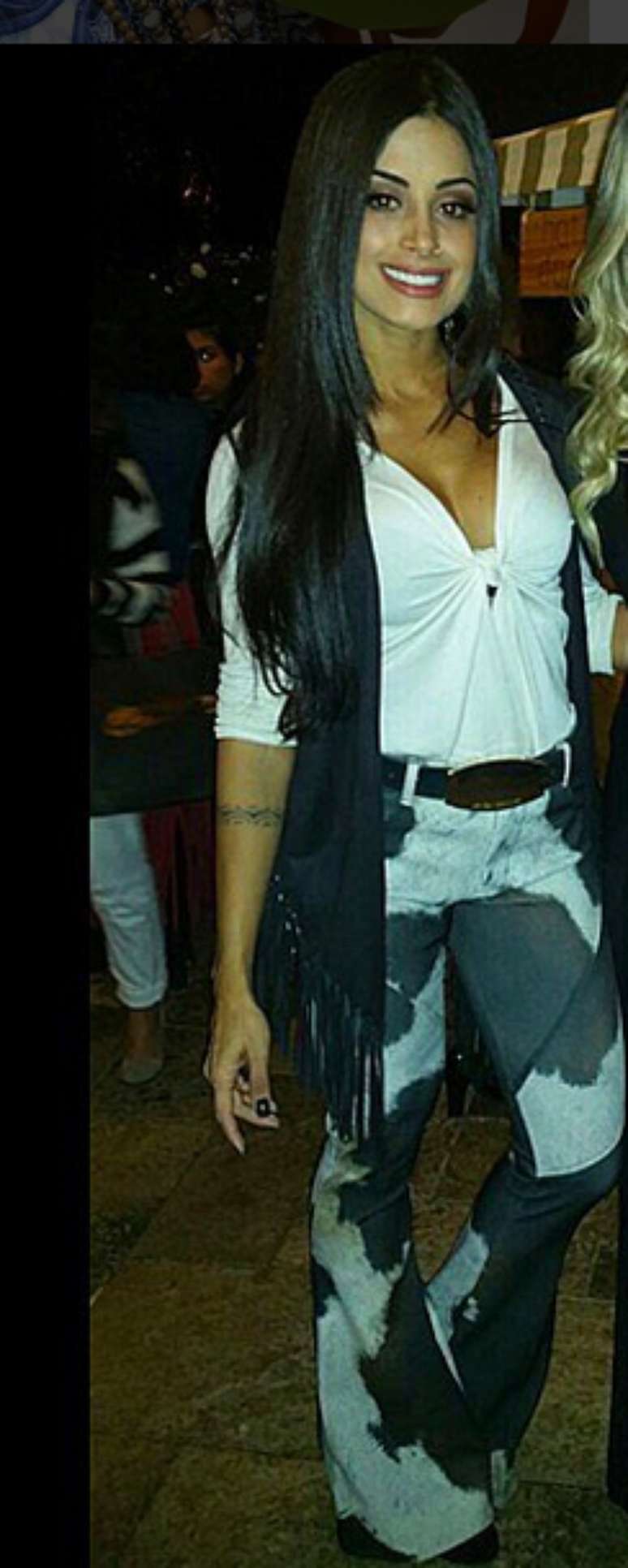 A calça flare com manchas de vaca é até legal, mas ficaria ainda melhor com uma blusa preta e pouco menos decotada