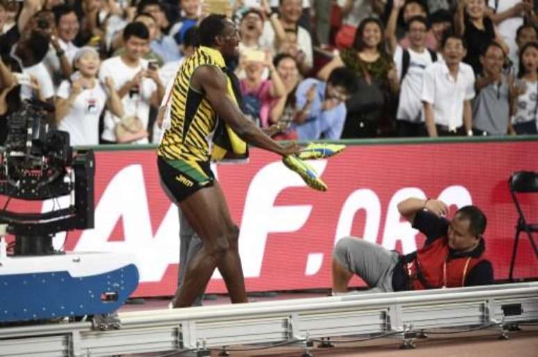 Bolt sorri enquanto cinegrafista tenta se levantar no estádio Ninho de Pássaro