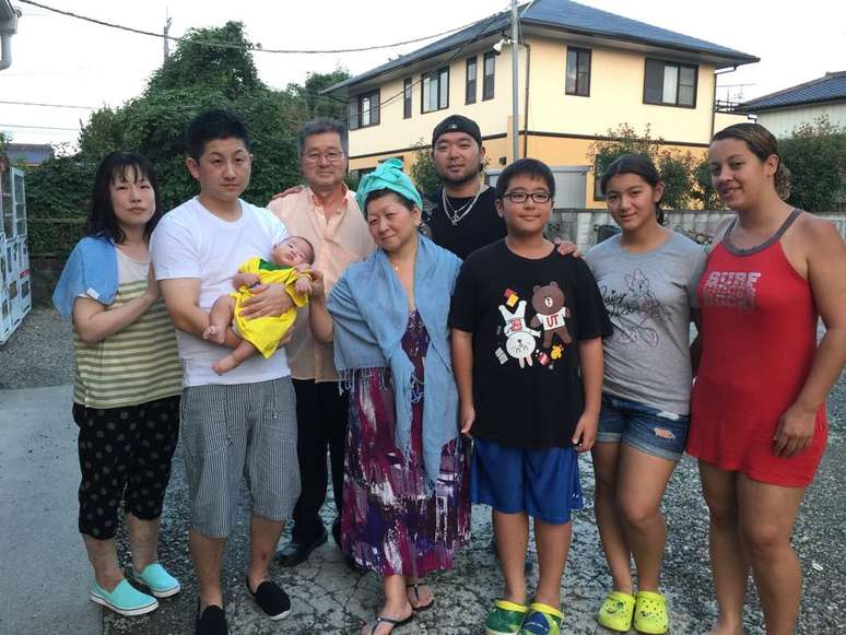 Alex (de boné) com a família, os pais e com o casal de japoneses e seu bebê, que ajudou a salvar da enchente