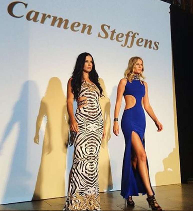 Adriana Lima, com longo em animal print estilizado, ao lado da alemã Toni Garnn, que exibe vestido azul com recorte na cintura e fenda