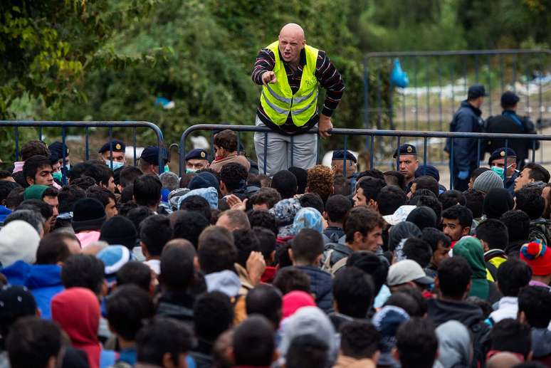 Voluntário dá instruções a migrantes que esperam para cruzar a fronteira entre a Croácia e Sérvia.