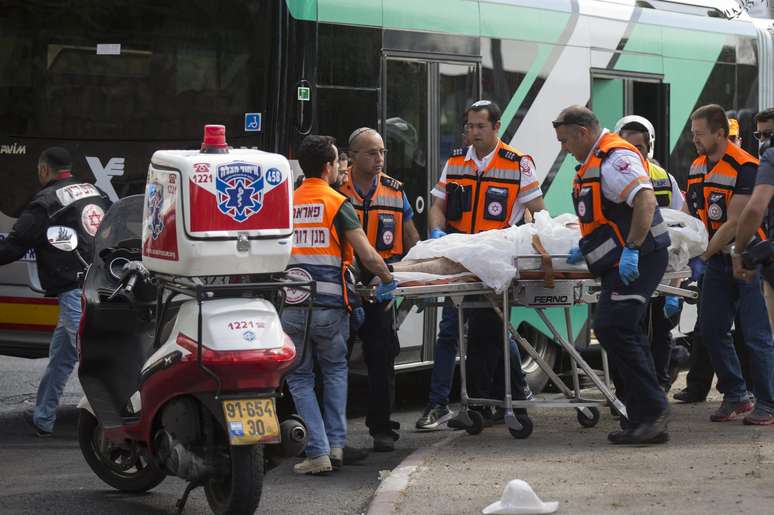 Serviços de emergência retiram um cadáver do ônibus onde pessoas foram atacadas no bairro Armon Hanatziv