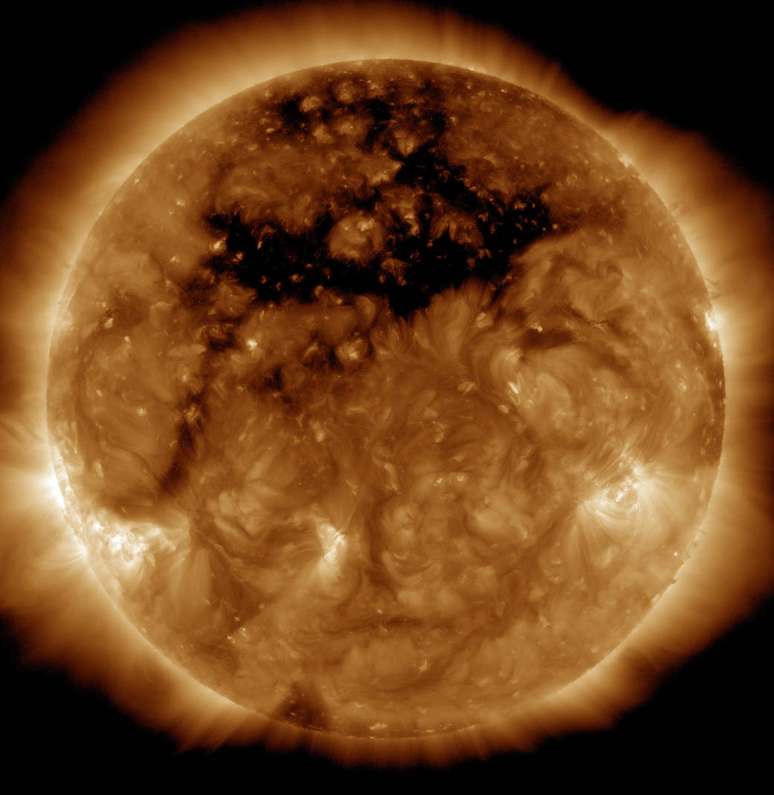 14 de outubro - A Nasa divulgou hoje uma foto que mostra a área escura na parte superior do sol, que é um buraco coronal, uma região onde o campo magnético do astro está aberto para o espaço interplanetário.