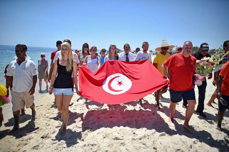 Turistas carregam bandeira da Tunísia após atentado terrorista na praia de Marhaba, em Sousse, que deixou 38 mortos em junho deste ano