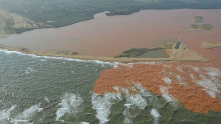 Foto aérea mostra lama chegando desembocando no mar na foz do Rio Doce em Regência-ES