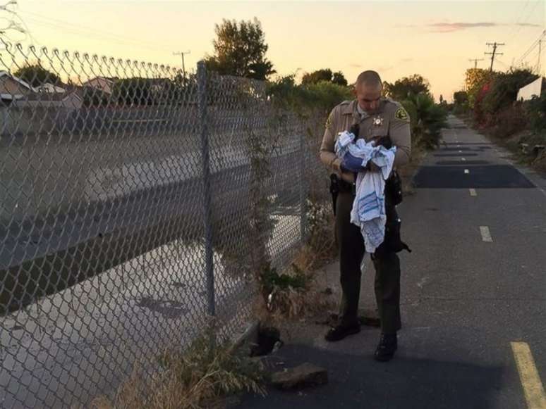 Agente carrega bebê que foi desenterrado vivo
