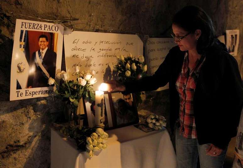 Salvadorenha acende vela para o ex-presidente, que morreu aos 56 anos de idade