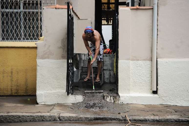 Morador limpa casa na rua Jiquibá, na Praça da Bandeira, após o temporal na noite de sábado (12) que deixou a cidade em estágio de crise