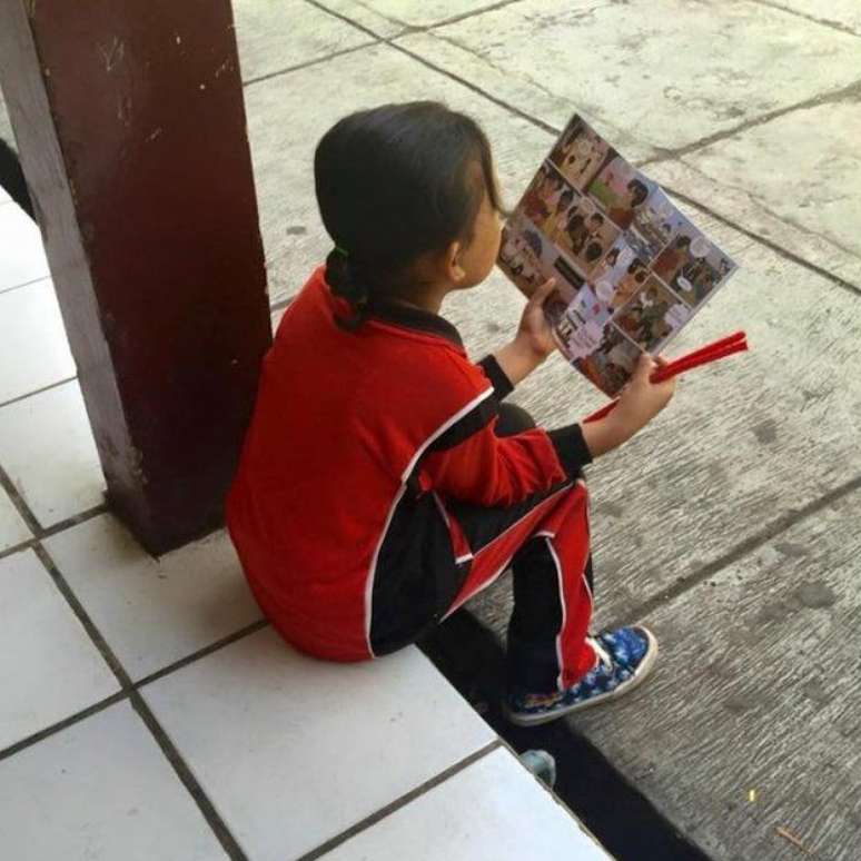 Menina indonésia lê quadrinhos que alertam para tráfico humano