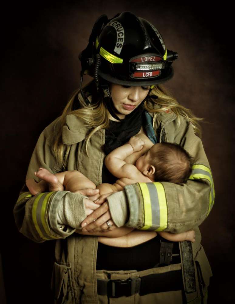 Mulher amamenta filho vestindo uniforme de bombeiro do marido