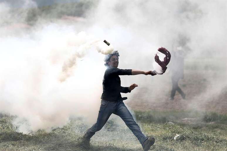 Refugiado lança de volta capsula de gás lacrimogêneo durante confronto no campo de refugiados de Idomeni