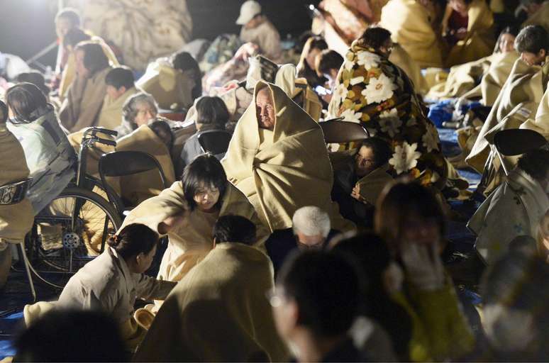 Moradores locais se enrolam em cobertores no meio da rua após um terremoto na cidade Mashiki, Kumamoto, Japão