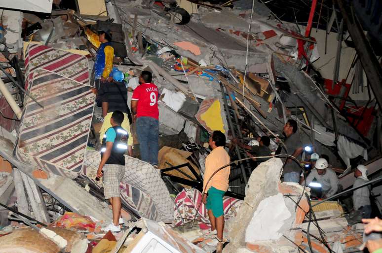 Grupo de pessoas busca sobreviventes nos escombros de um edifício em Manta, Equador. 