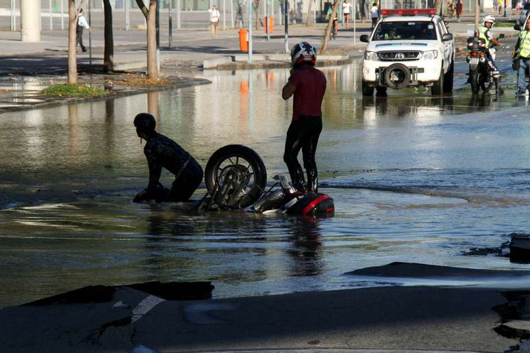 Motociclista e garupa caem em buraco que se abriu após rompimento de uma tubulação da Cedae e que interdita os dois sentidos da Radial Oeste, zona norte do Rio de Janeiro