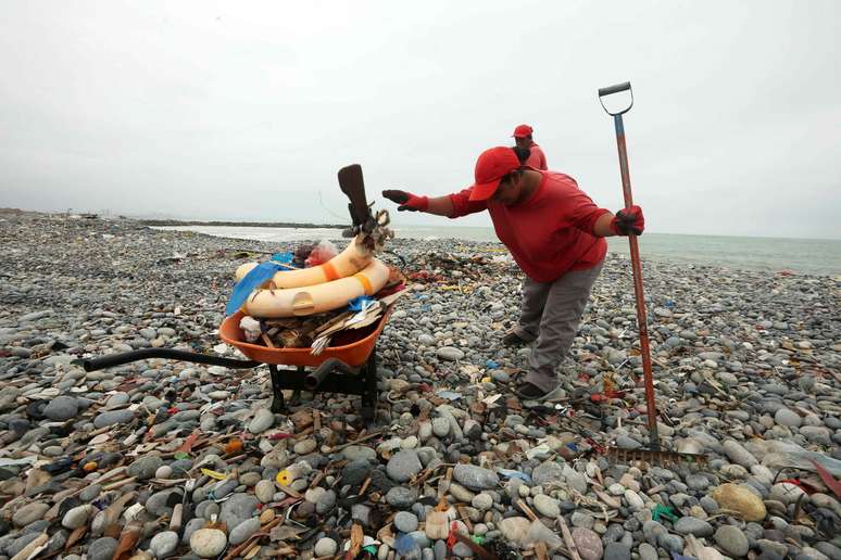 Uma trabalhadora de limpeza recolhe restos plásticos e outros materiais de construção que são &amp;#034;cuspidos&amp;#034; diariamente pelo oceano Pacífico à praia Carpayo, situada no Callao, a cidade portuária de Lima