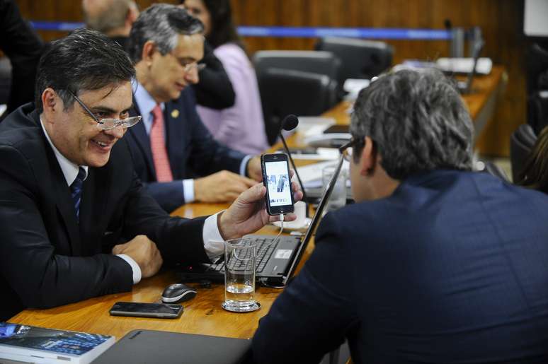 Senador Cássio Cunha Lima (PSDB) mostra a Lindbergh Faria (PT) uma imagem em que a presidente Dilma parece ser transpassada por uma espada. A imagem foi feita pelo fotógrafo Wilton de Sousa Júnior em uma cerimônia militar em 2011.