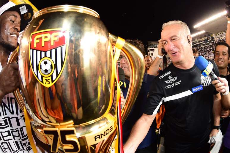 Dorival Júnior sorri ao lado da taça e campeão paulista