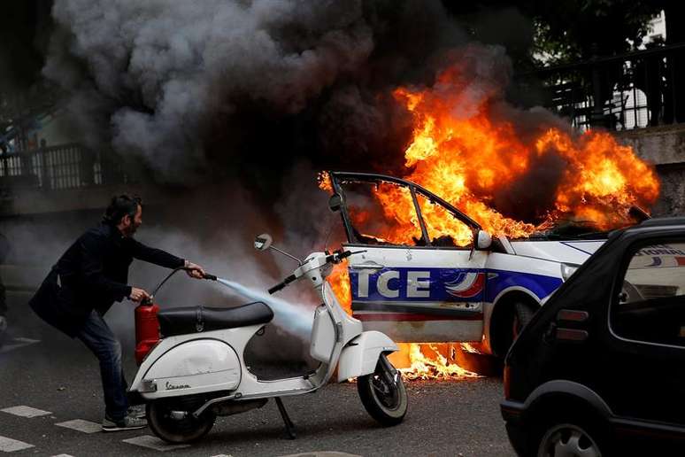 Homem tenta apagar fogo em carro da polícia durante protesto não autorizado contra a violência policial nas manifestações contra a reforma trabalhista 