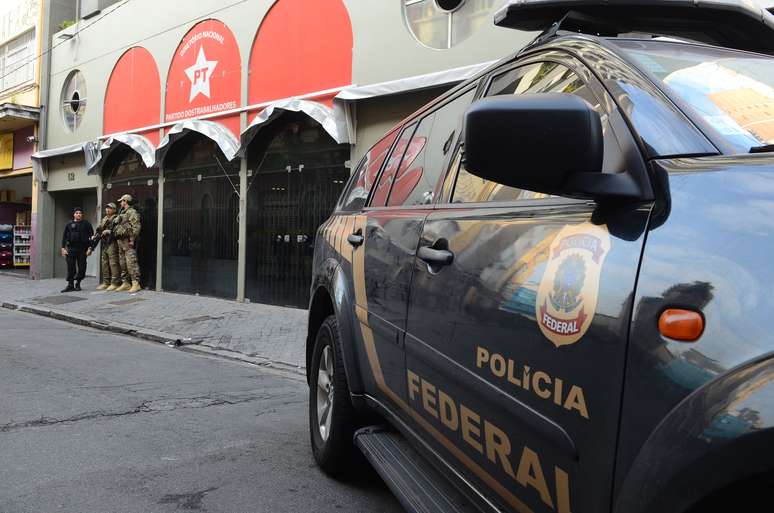 Oito homens armados do Grupo de Pronta Intervenção da Polícia Federal fazem a segurança do lado de fora da sede do prédio, auxiliados por policiais militares. 