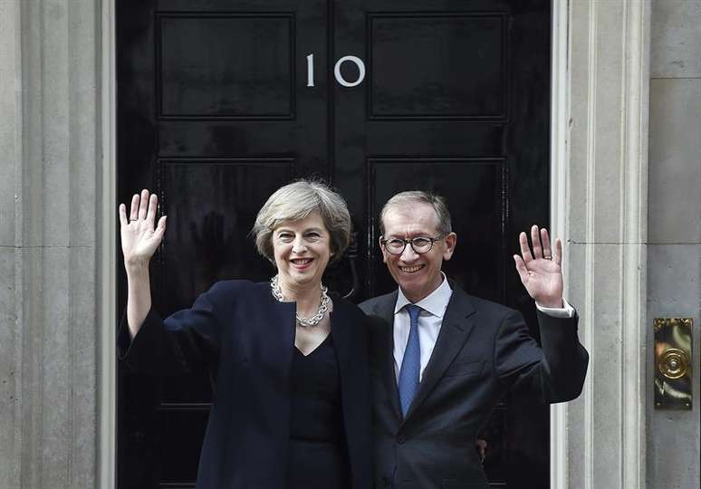 A nova primeira-ministra britânica, Theresa May, e seu marido Philip, saúdam os repórteres em sua chegada à residência oficial, no número 10 da Downing Street.