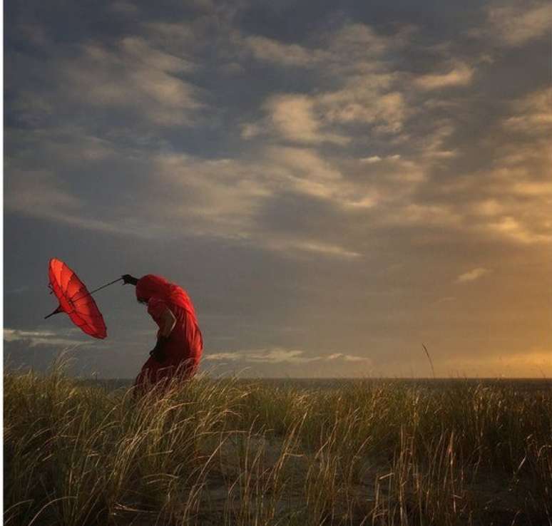 “Ela se dobra com o vento” é o título da fotografia do americano Robin Robertis, que ficou em segundo lugar no concurso. “Estava em um curso para iPhone quando todos saímos para fotografar o entardecer”, relata. “Uma das coisas que sempre carrego quando viajo é este magnífico guarda-chuva vermelho. Enquanto outros registram fotos de paisagens bonitas, gosto de captar aspectos humanos dentro da cena”