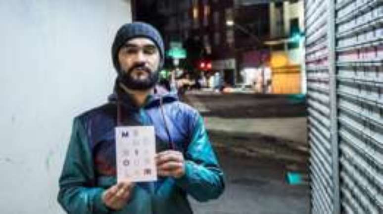 S&eacute;rgio Silva no cruzamento em que foi alvejado, segurando livro sobre o ocorrido, 'Mem&oacute;ria Ocular', escrito pelo jornalista Tadeu Breda