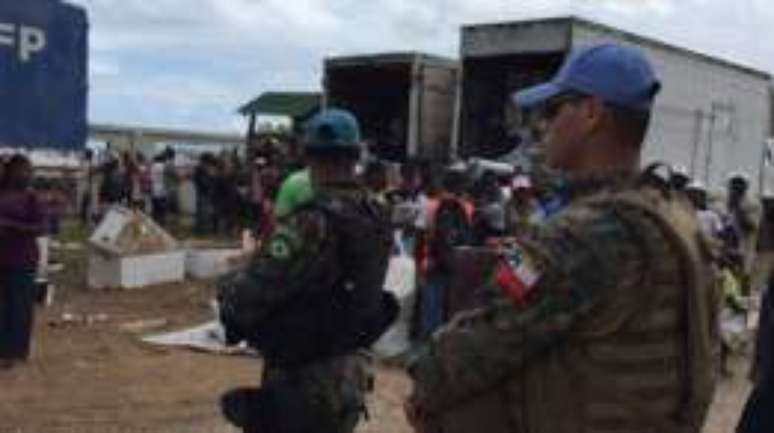 Militares chilenos e brasileiros protegem carregamentos de comida e suprimentos no sul do Haiti.