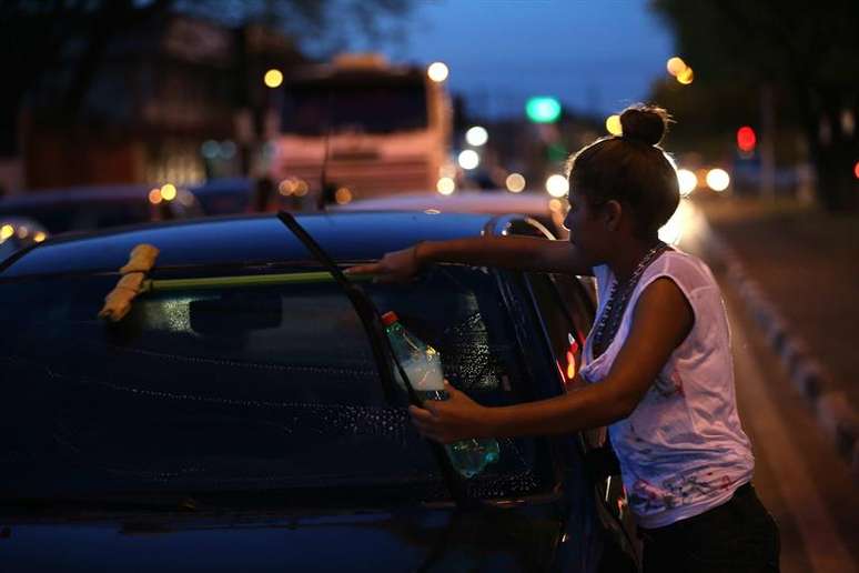 Venezuelana limpa para-brisa de carro na esquina da rua Mario Homem de Melo com a avenida Venezuela