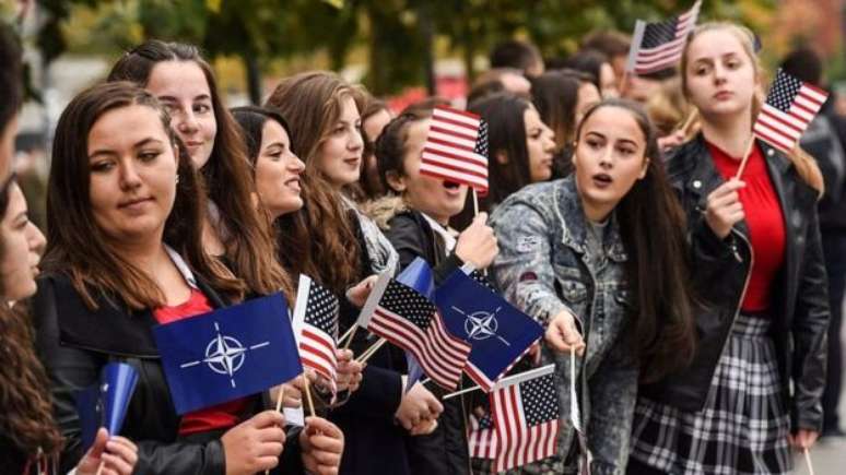 Jovens em Kosovo mostram bandeiras dos EUA e da Otan durante competição do Exército americano e da força de segurança de Kosovo em Pristina. Aproximadamente 4.600 soldados liderados pela Otan ainda estão presentes no Kosovo 