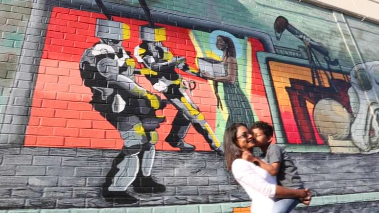 A enfermeira e o filho posam em frente a grafite feito em sua homenagem.