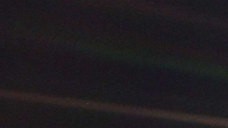 Uma foto escura, em que não se vê nada? Olhe novamente com atenção. O minúsculo pontinho claro é a Terra, a seis bilhões de quilômetros, onde estava a sonda Voyager em 1990. A faixa mais clara sobre o fundo escuro é um raio de luz dispersada.