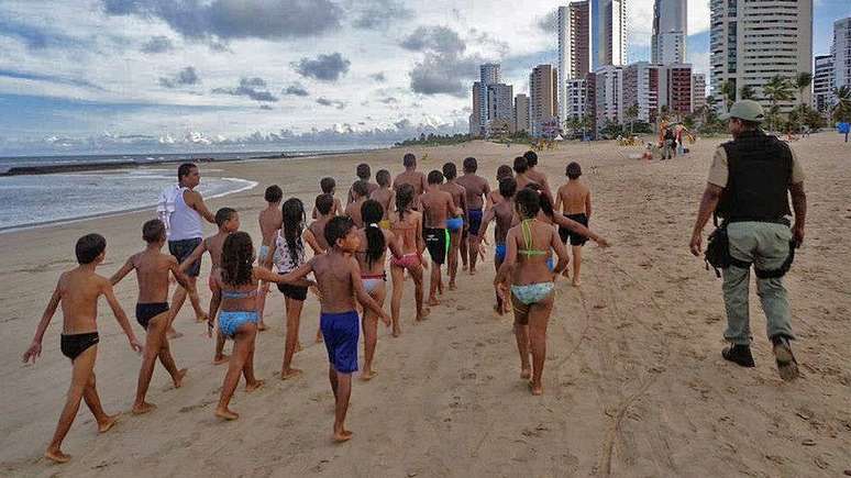 Aula de educação física na praia no Recife com crianças da Ilha de Deus, no projeto Patrulheiro Mirim, aproximam comunidade e PM
