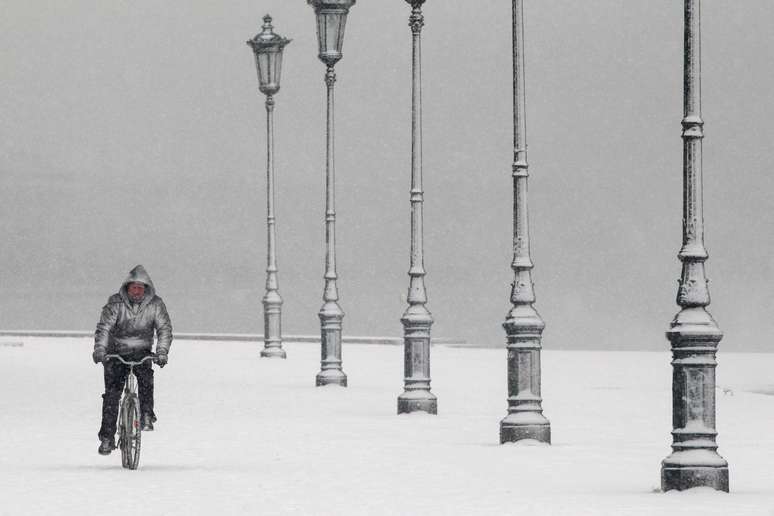 Homem anda de bicicleta debaixo de nevasca na Grécia.