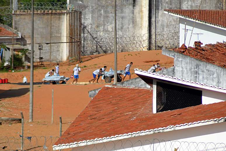 Corpos de presos assassinados durante rebelião são retirados de presídio no Rio Grande do Norte.