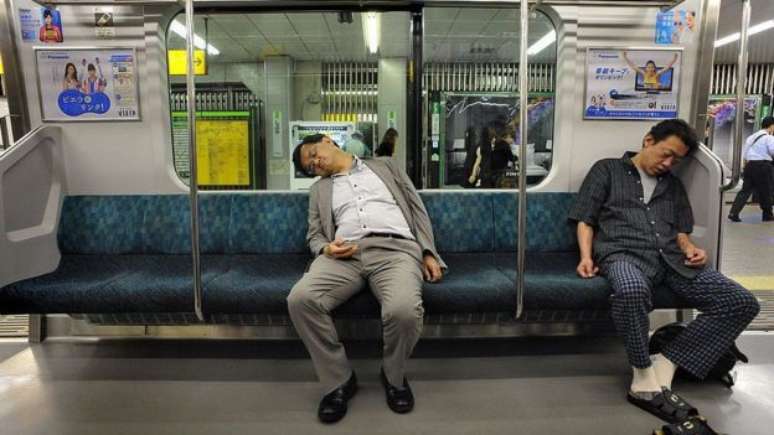 Um sinal de status? Dois homens dormem em um trem do metrô de Tóquio