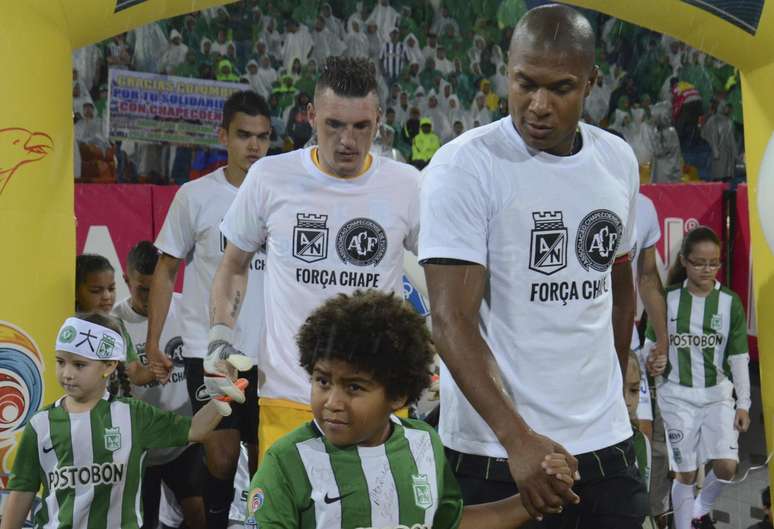Jogadores do Atlético Nacional entram em campo para partida pelo Campeonato Colombiano usando uma camiseta em solidariedade às vítimas da tragédia com a Chapecoense