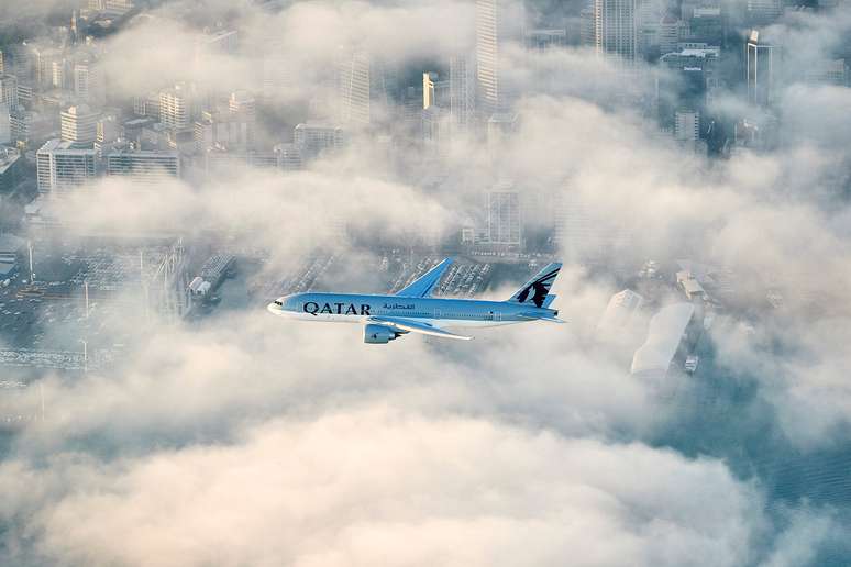 Avião da Qatar sobrevoa a cidade de Auckland em sua aproximação final.
