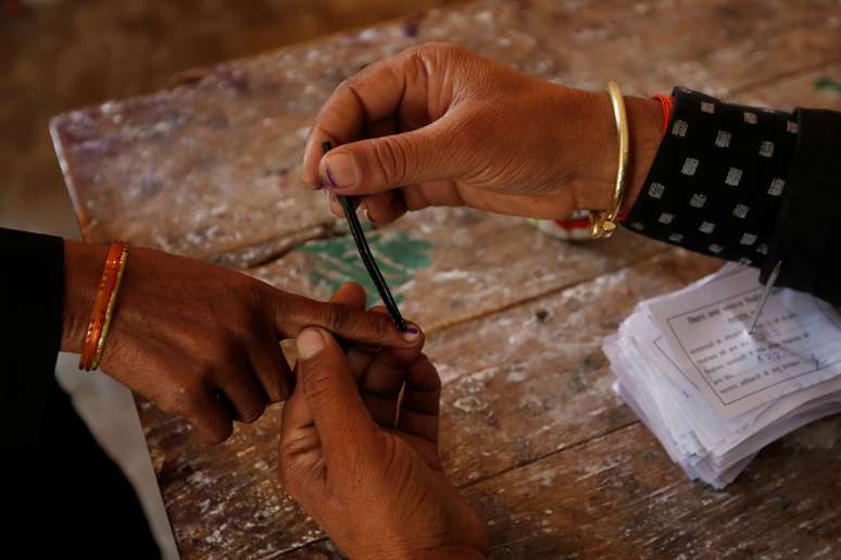 Mulher tem o dedo pintado depois de votar nas eleições na Índia