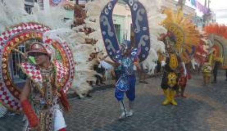 O estandarte da Troça Carnavalesca Ceroula de Olinda dançou em meio a homens fantasiados com grandes costas de penas e brilho 