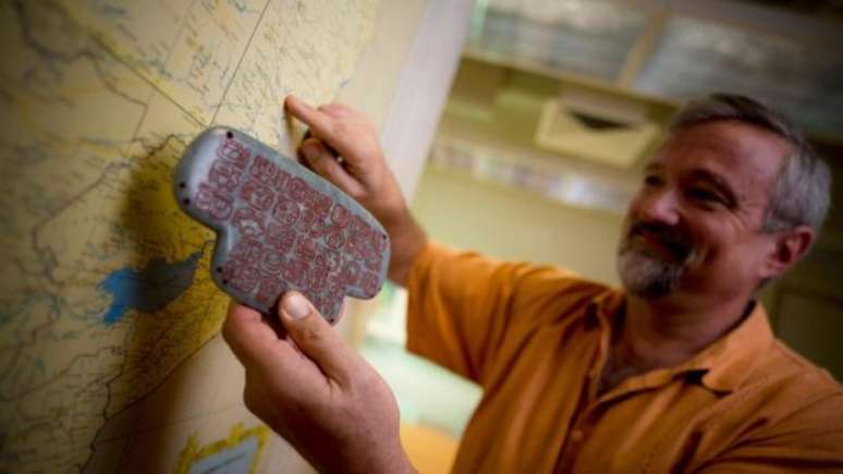 Geoffrey Braswell, arqueólogo da Universidade da Califórnia, segura uma réplica do pingente 