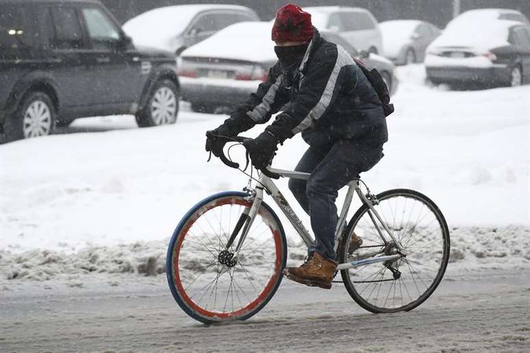 Homem utiliza bicicleta em Nova York em dia de tempestade de neve.