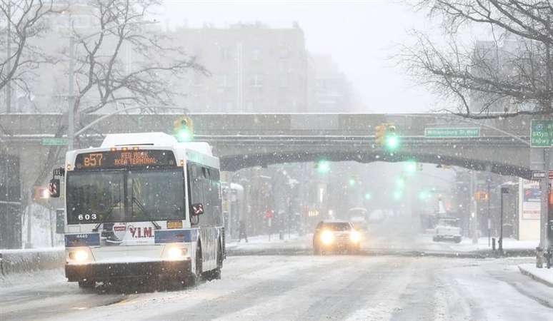 Ônibus circula por rua escorregadia no Brooklyn após tempestade de neve.
