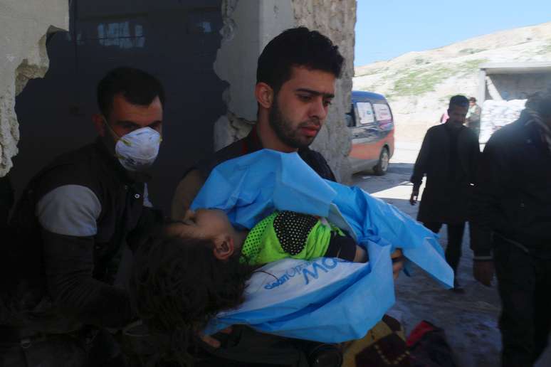 Na foto, um homem carrega o corpo de uma menino morto após ataque químico na Síria