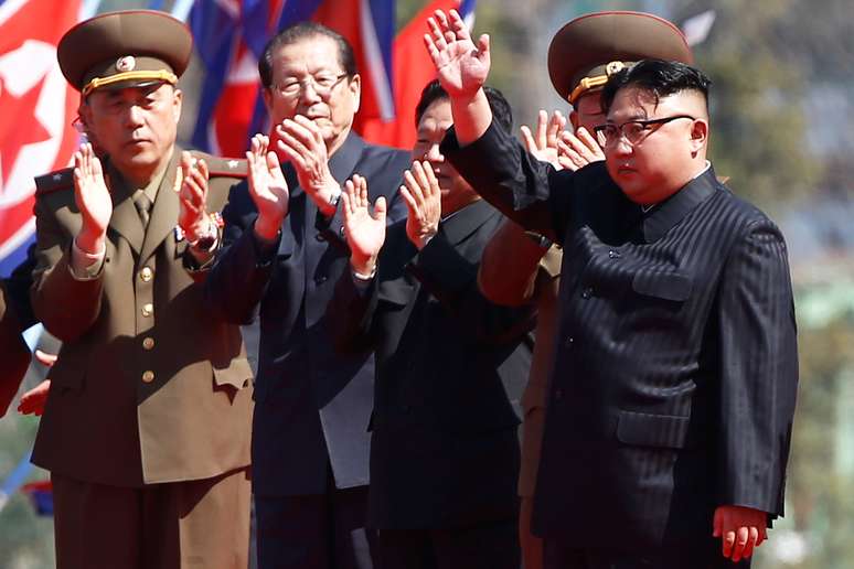 Kim Jong-un (à direita) acena para a população durante evento na Coreia do Norte.