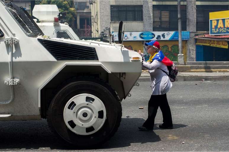 Membros da imprensa e outros manifestantes tentarm tirá-la de frente do tanque sem sucesso