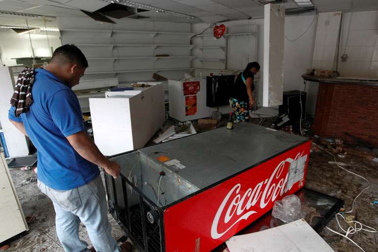Homem procura por objetos de valor em loja de conveniência saqueada em Caracas, na Venezuela