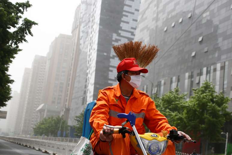 Limpador de rua usa máscara para se proteger durante tempestade de areia em Pequim