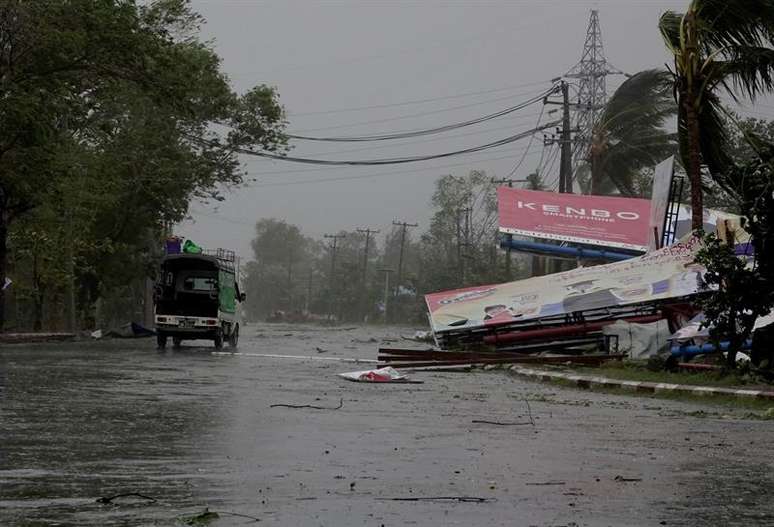 Veículo circula ao lado de placas publicitárias caídas com a passagem do ciclone Mora.