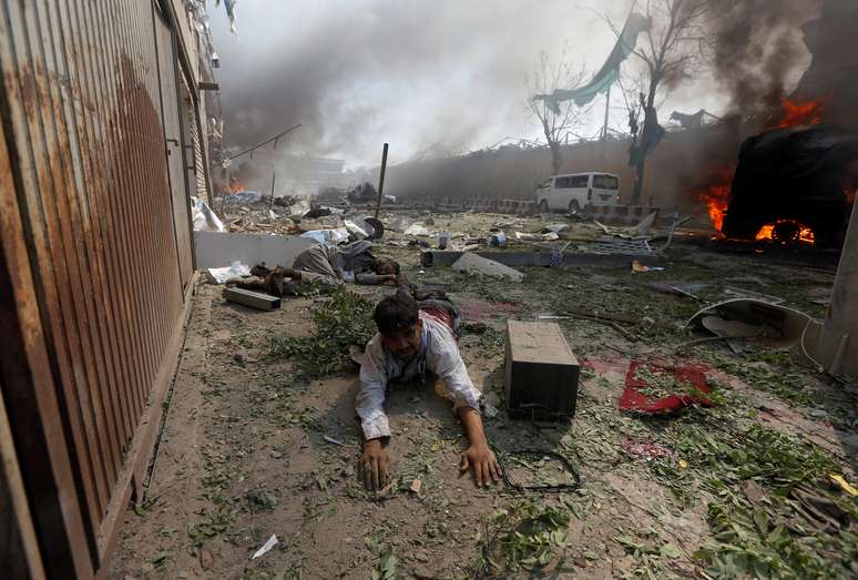 Homem ferido é fotografado ao lado do local da explosão de carro-bomba